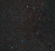 Thousands of stars fill the frame, almost entirely covering the dark background. A few of them are larger than the others and shine in blue, whitish, and orange. The black hole BH3 is not visible in the image.