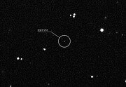 A dark image is but a very magnified small region of the night sky. White spots represent stars and other astronomical objects, with different brightness of white. The location of the asteroid 2024 YR4 is highlighted at the center, which appears as a tiny spec of light.