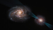 This image is an artist’s impression of two galaxies involved in a galactic merging event, shown as two spirals of gas and dust, glowing with blue, pink and purple light and sprinkled with glittering stars. From the bright centre of the galaxy on the right of this image, a thin cone of light - a quasar - is shining into the galaxy on the left, digging a hole through the edges of this galaxy as it destroys galactic material in its path.
