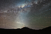 Eine weitwinklige Nachtaufnahme der Atacama-Wüste unter einem von unzähligen Satellitenspuren durchzogenen Sternenhimmel. Am unteren Bildrand erstreckt sich die dunkle Silhouette einer bergigen Wüstenlandschaft. Zentral auf der Spitze des höchsten Hügels im Vordergrund steht die beleuchtete, kuppelförmige Baustelle des Extremely Large Telescope (ELT).

Vom Horizont weit hinter dem Hügel ragen vier dünne, orangefarbene Laserstrahlen des Paranal-Observatoriums vertikal in den Himmel. Der obere Teil des Bildes wird vom bandförmigen, detailreichen Leuchten der Milchstraße dominiert, die sich diagonal von links nach rechts erstreckt und von dunklen Staubwolken durchsetzt ist.

Das gesamte Himmelszelt ist von einem dichten, chaotischen Netz aus Hunderten geradlinigen Lichtspuren überzogen. Diese Linien verlaufen in alle Richtungen und kreuzen sich vielfach. Besonders im linken unteren Quadranten, nahe dem Horizont, ist die Dichte der weißlichen Satellitenspuren so extrem, dass sie ein fast geschlossenes, helles Geflecht bilden, das den Blick auf die Sterne dahinter blockiert. Einige wenige, horizontal verlaufende Spuren im rechten Bildbereich bestehen aus rot-weiß gestrichelten Linien, die von den Blinklichtern vorbeifliegender Flugzeuge stammen.