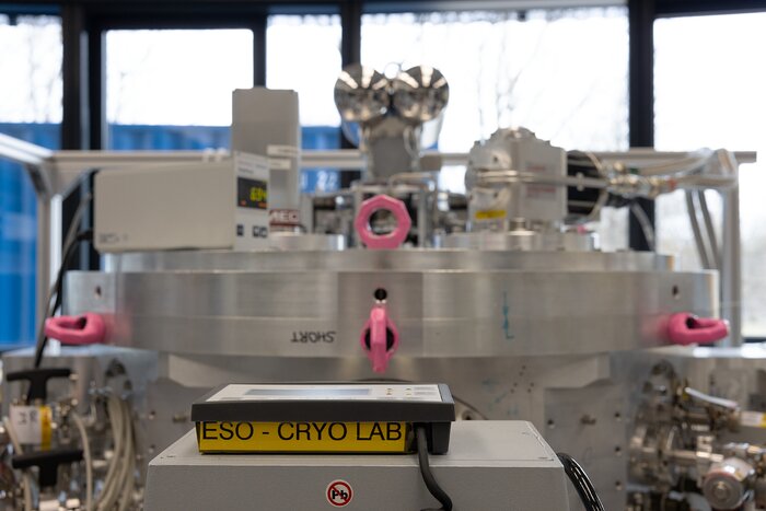 A large, round, metallic structure looms in the background of this image, and just in front of it sits a box labelled 