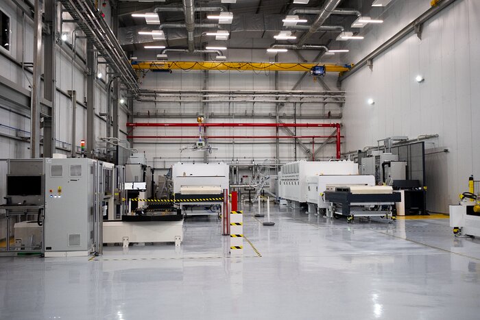 This image shows a large laboratory, including two large chambers alongside complicated machinery on either side of the image, and a crane hanging over the left chamber.