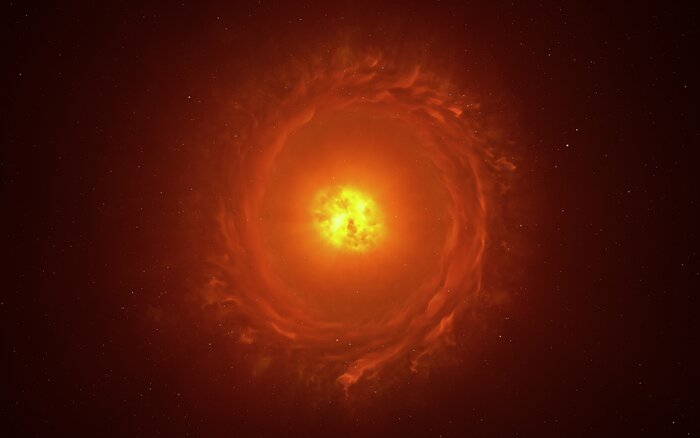 The image shows a star embedded within a bright yellow to orange cocoon of dust. Both are located inside a massive torus (or ring) of dust, portrayed in a dimmer, darker hue of red. The cocoon is at an intermediate inclination with respect to the torus, neither parallel nor perpendicular to it.