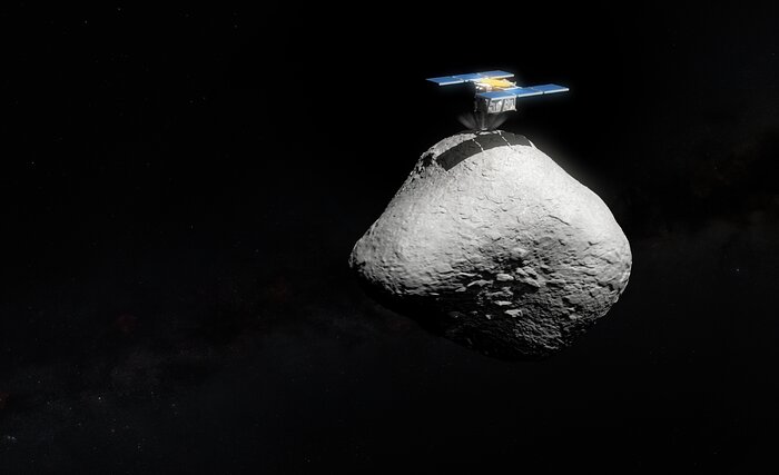 Künstlerische Darstellung einer Raumsonde, die auf einem unregelmäßig geformten Asteroiden landet. Der graue, felsige Asteroid schwebt im schwarzen Weltraum. Auf seiner Oberfläche sitzt die Sonde mit rechteckigen, blauen Solarpaneelen und einem zentralen, goldfarbenen Modul. Der Hintergrund ist weitgehend dunkel, mit schwachen Sternen und Andeutungen der Milchstraße.