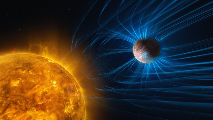 An illustration of a planet orbiting a star. The star is a huge yellow sphere with a hot “bubbling” surface. The planet is a gas giant, completely covered with clouds that are smeared due to the planet’s fast winds. The planet is surrounded by a magnetic shield of sorts, depicted with blue lines curving away from the star.
