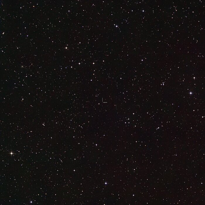 A telescopic image of a starry field. Two perpendicular white lines mark a faint white star at the centre of the image.