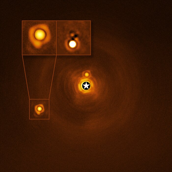 The image has a yellow/orange tone, with three small circular features. Each of the features has ripples surrounding it, like stones dropped in a pond. At the centre is the largest, brightest spot. This is the central star (A), and just above it is a smaller spot, the companion object B. In the bottom left quadrant of the image are the second star (C), and its newly discovered companion (Cb). Two closeup insets show Cb in more detail.