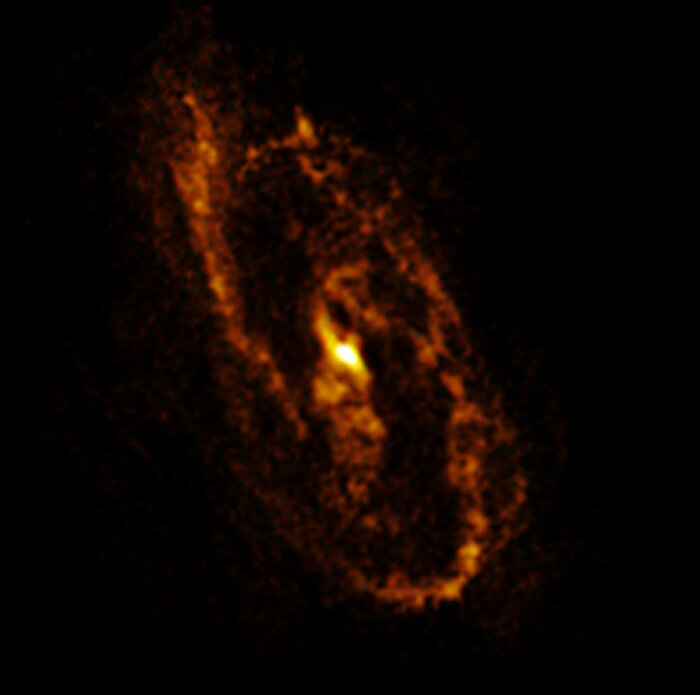 The image shows an elongated ring of golden clumpy clouds against a black background.